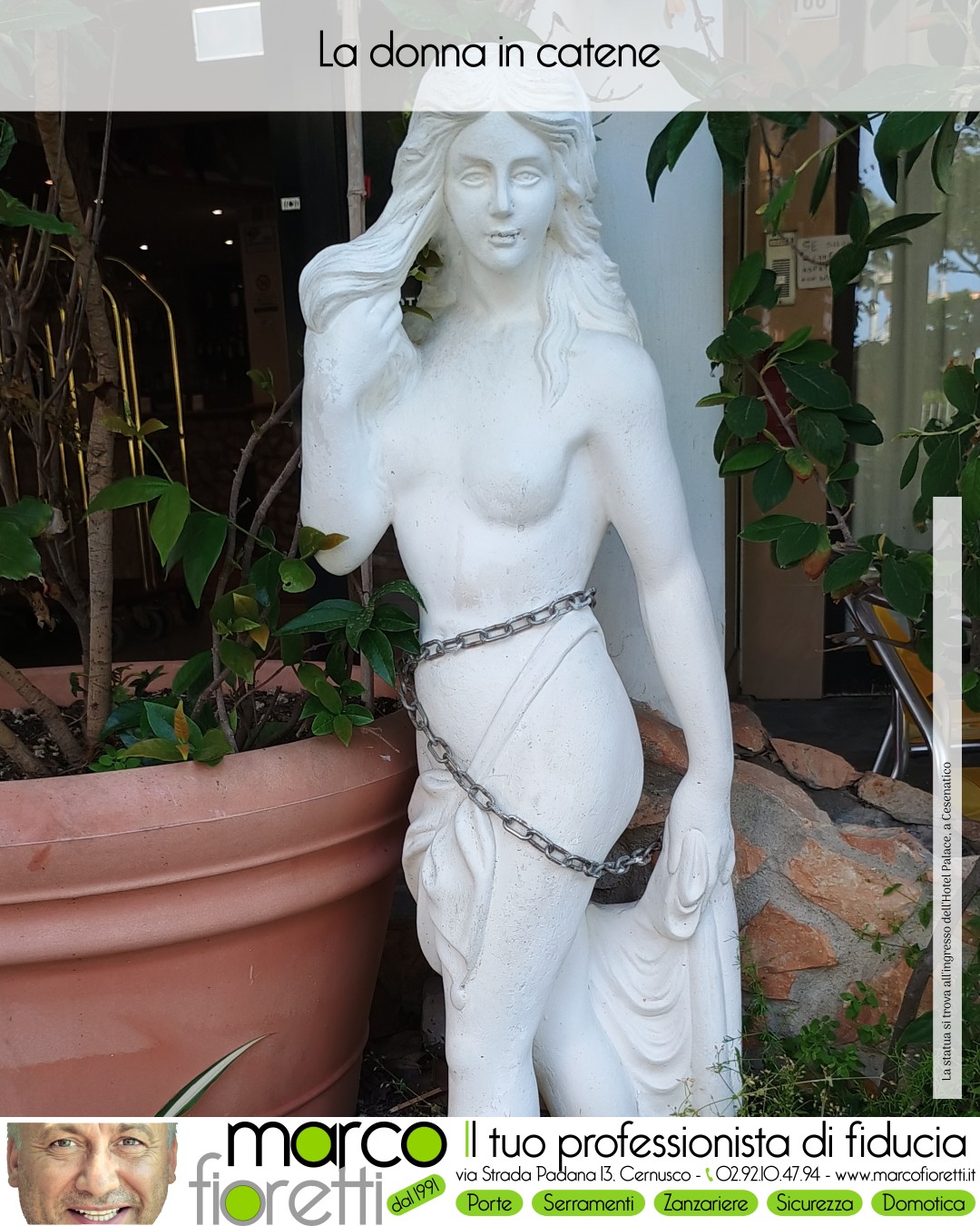 Statua femminile bianca con una catena intorno al corpo davanti a un ingresso.